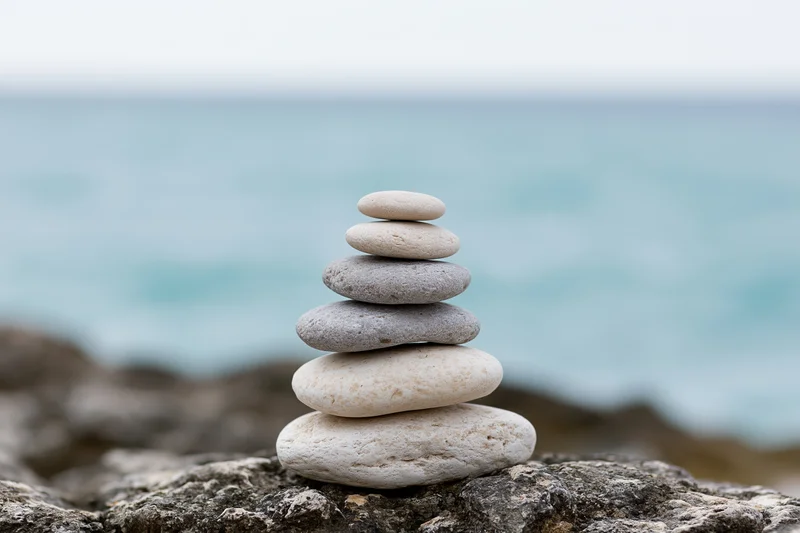 Balanced stack of smooth stones on rocky shore by the ocean