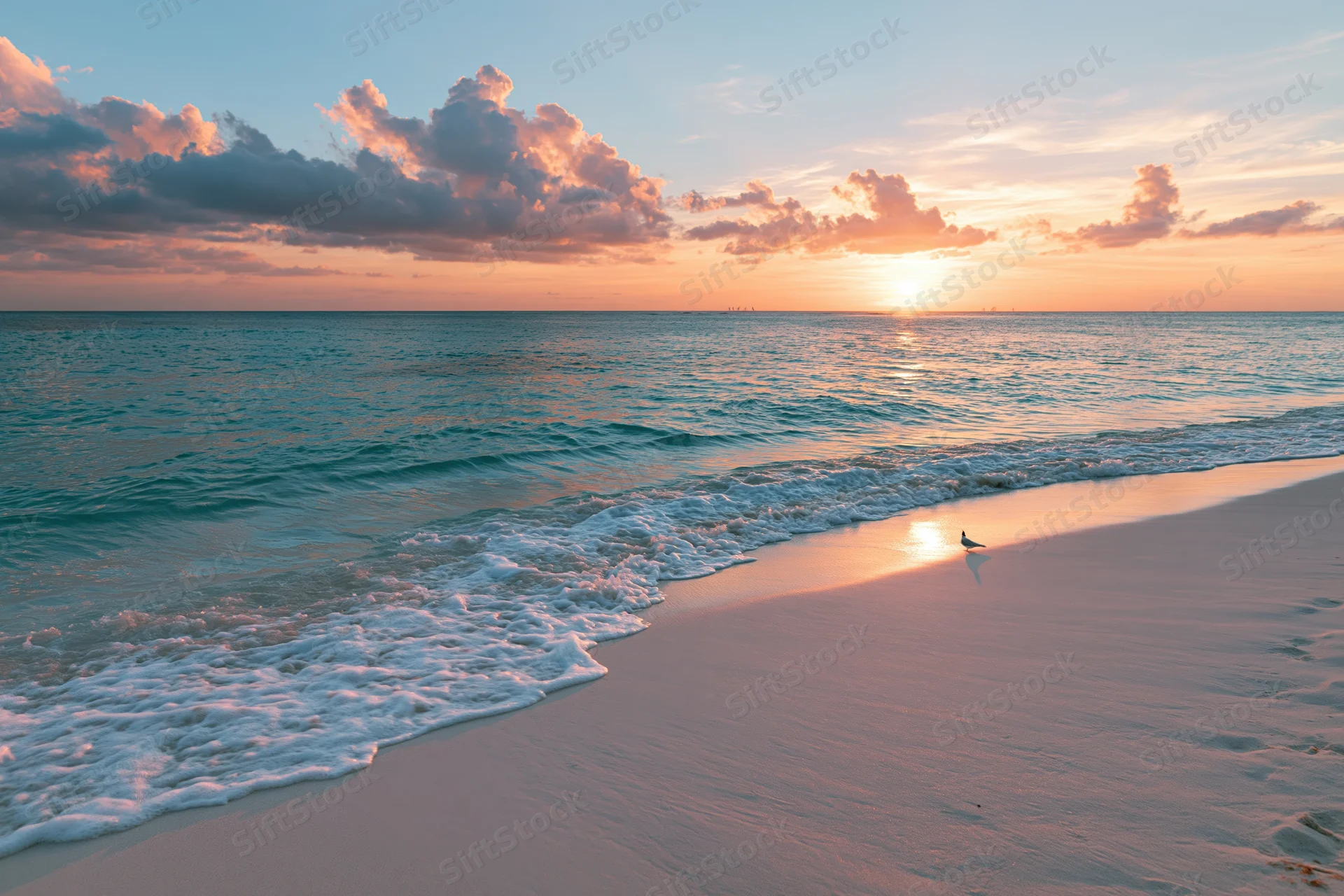 Waves rolling onto a sandy beach at sunset with clouds in the sky