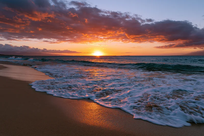 Sunset over ocean waves washing onto sandy beach at twilight