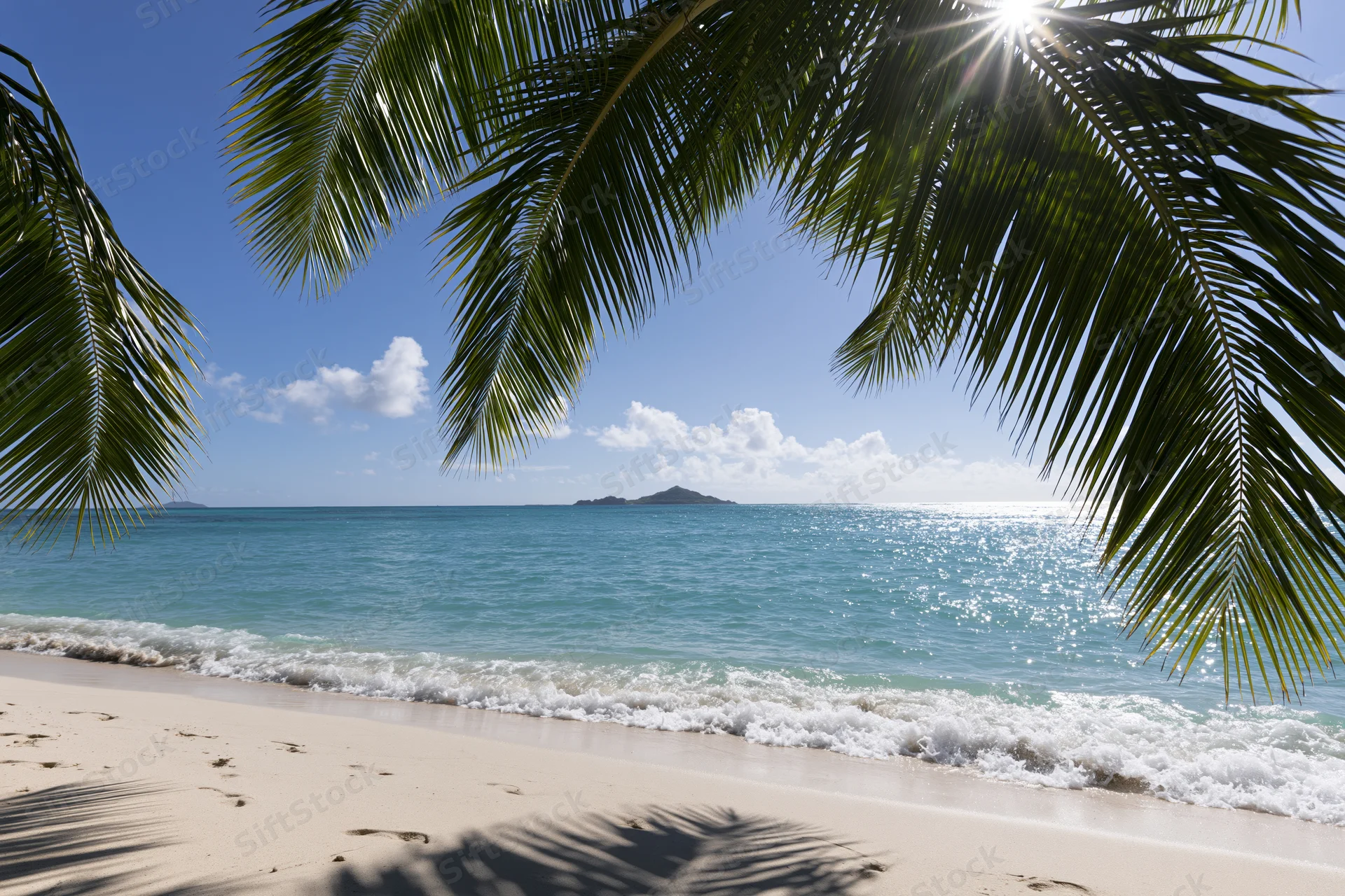 Palm fronds framing a tropical beach with turquoise ocean and distant island under bright sun