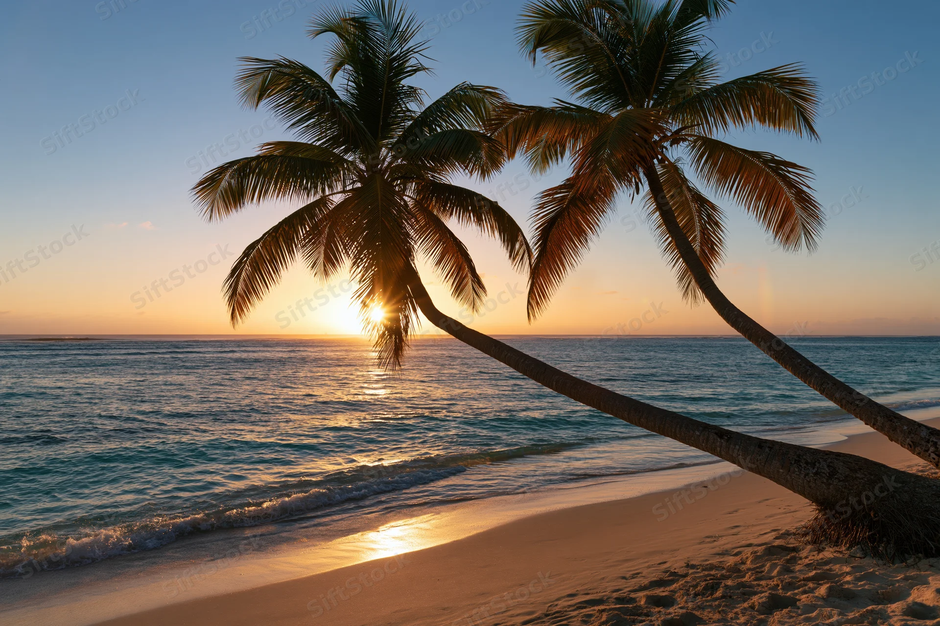 Palm trees leaning over sandy beach at sunset with ocean waves and golden sky