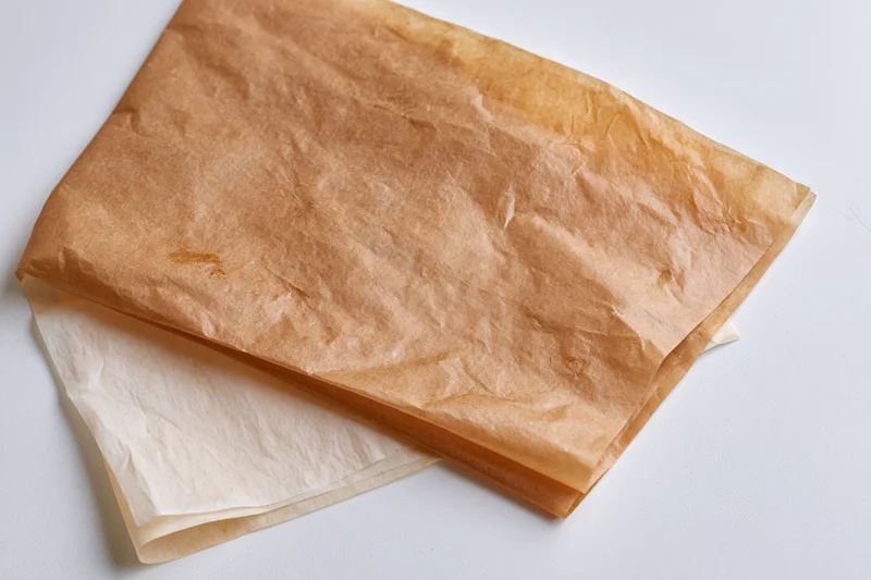 Crumpled brown and white parchment paper sheets on white surface