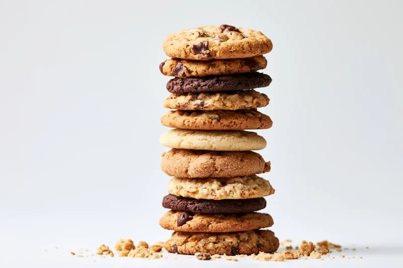 Stack of assorted cookies with crumbs on white background