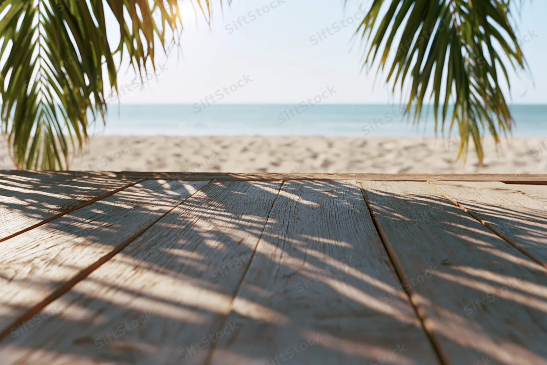 Wooden deck with palm fronds framing a sandy beach and ocean view