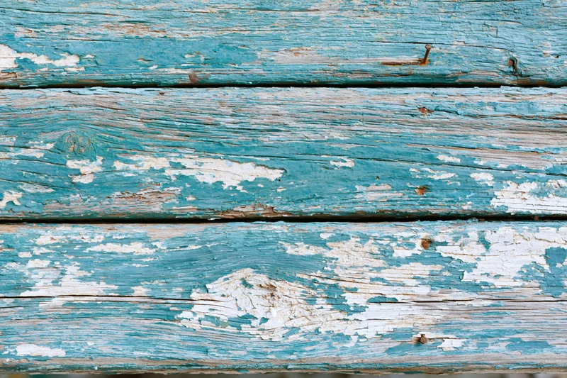 Weathered blue-painted wooden planks with peeling paint and visible grain