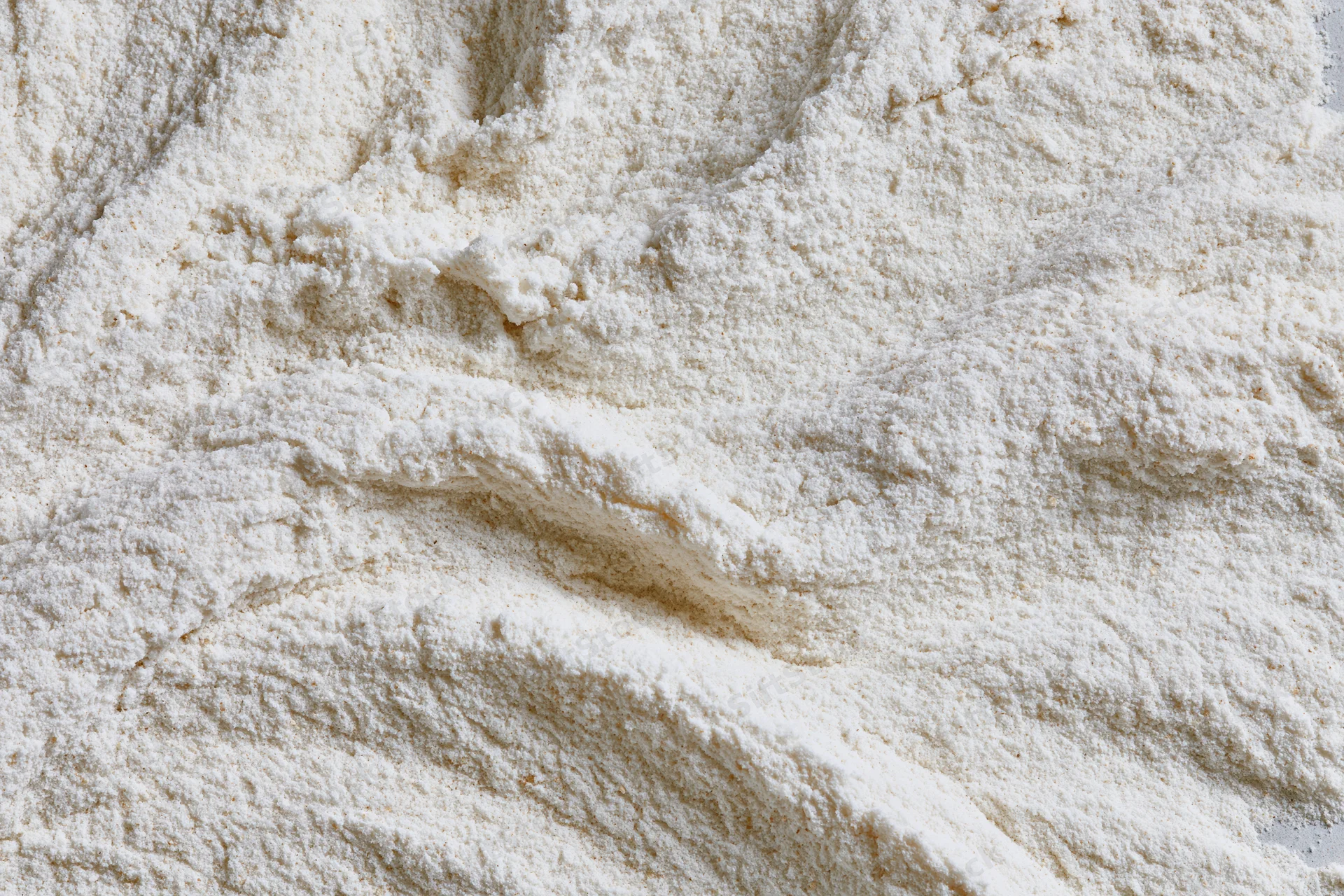 Closeup of white flour pile showing fine granular texture and soft surface details