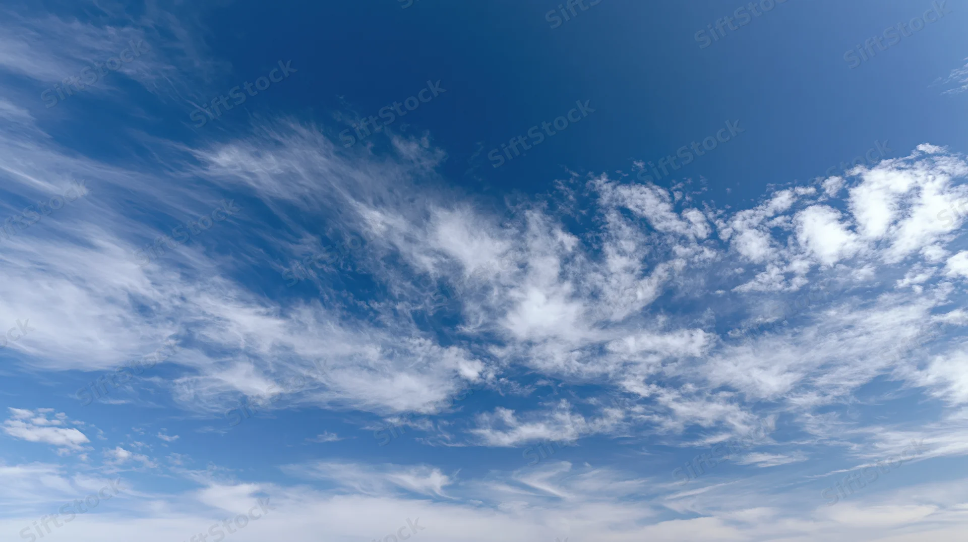 Blue sky with scattered white wispy clouds across the horizon