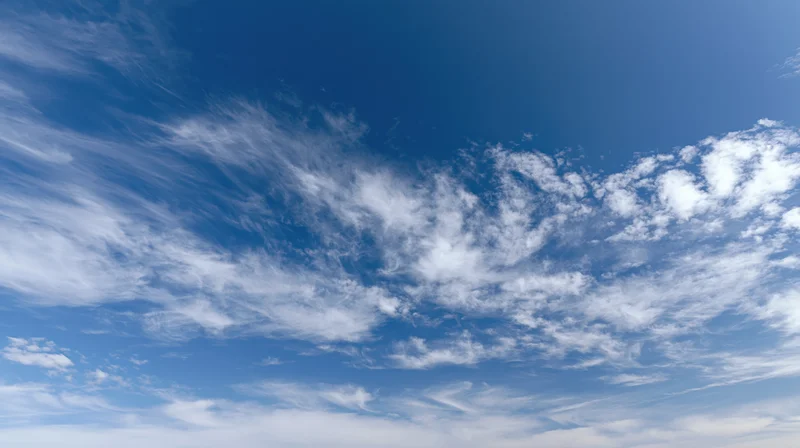 Blue sky with scattered white wispy clouds across the horizon