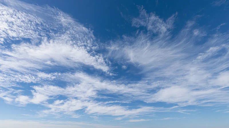 Wispy white cirrus clouds scattered across a clear blue sky during daytime