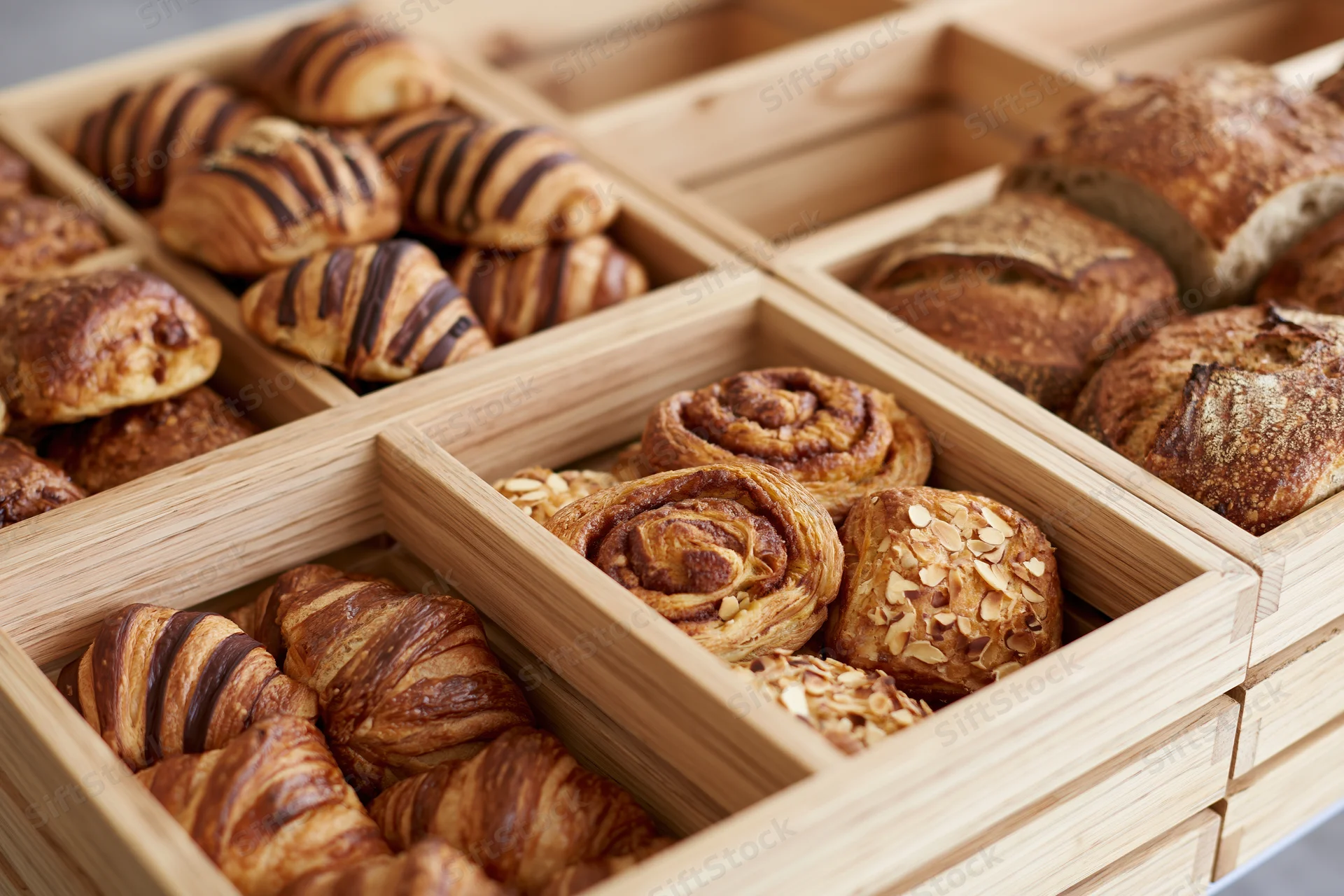 Assorted baked goods arranged in wooden compartments on a bakery display tray