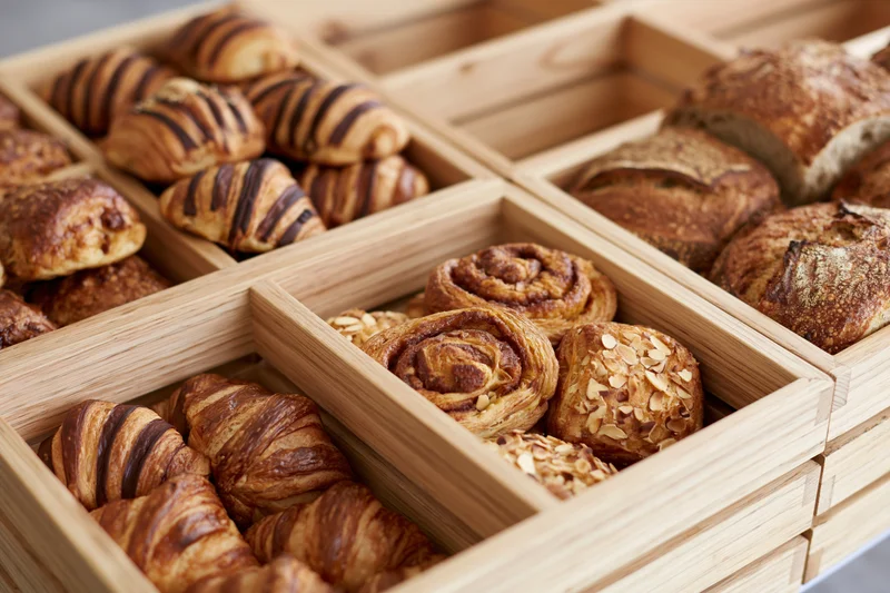 Assorted baked goods arranged in wooden compartments on a bakery display tray