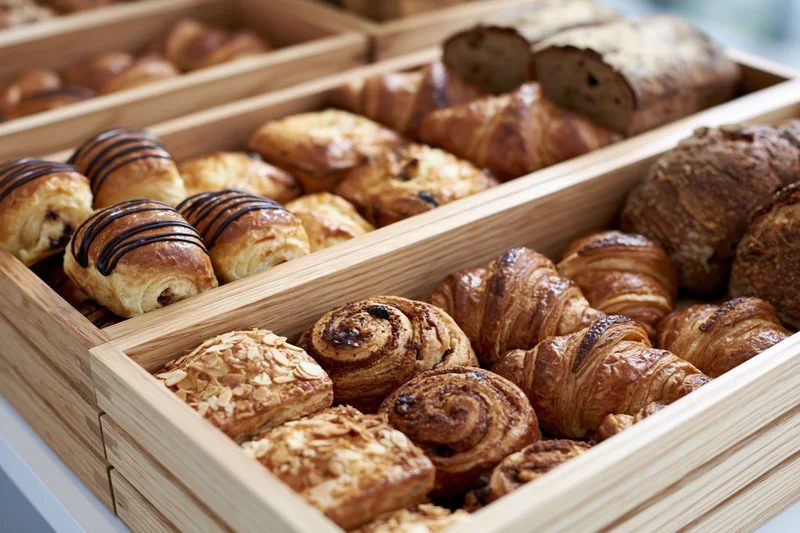 Assorted pastries arranged in wooden trays in a bakery display