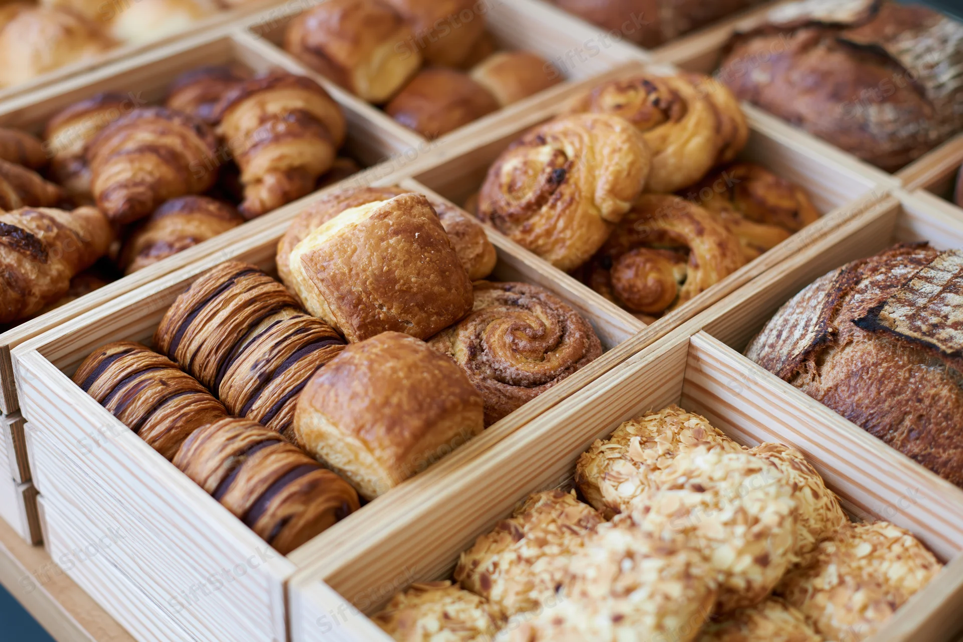 Assorted baked goods arranged in wooden boxes for display in a bakery