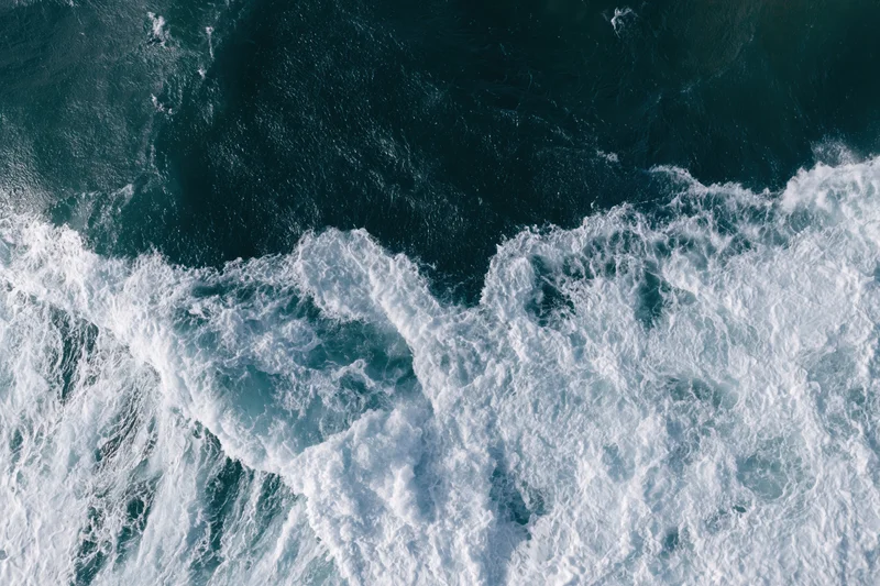 Aerial view of ocean waves breaking with white foam and deep blue water