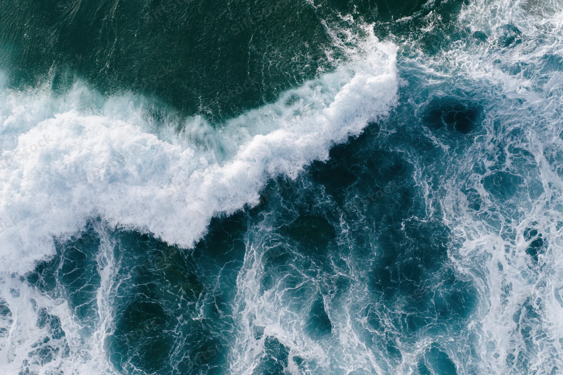 Aerial view of crashing ocean waves with white foam and deep blue water