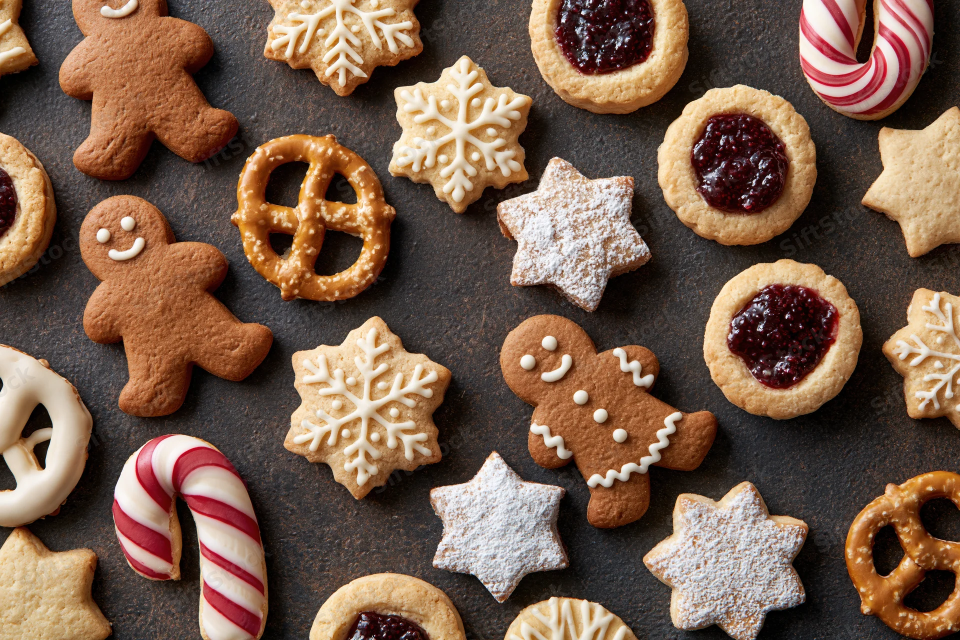 Assorted christmas cookies and candy arranged on dark surface