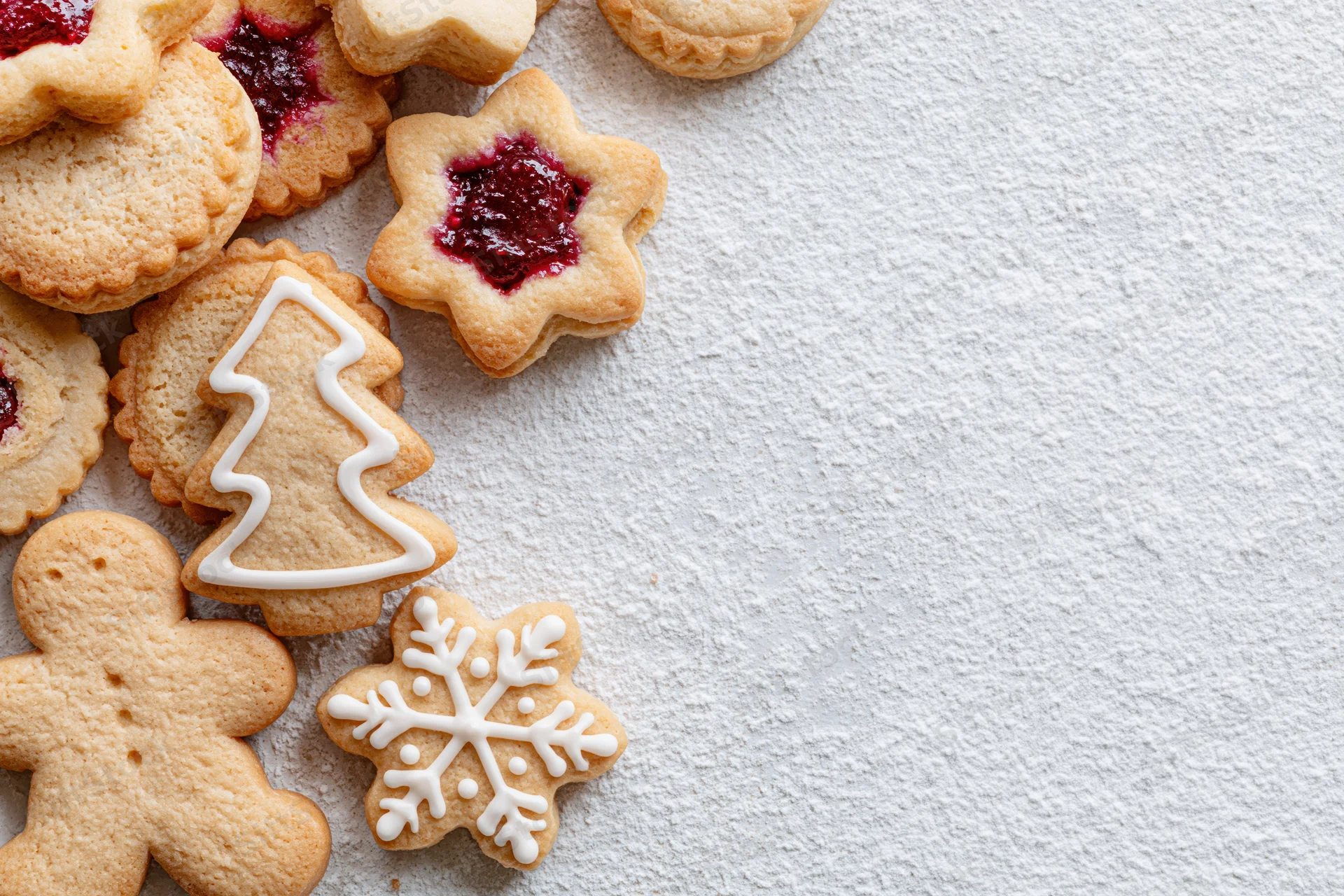 Christmas cookies shaped like trees, snowflakes, and gingerbread men with jam and icing on a white textured surface