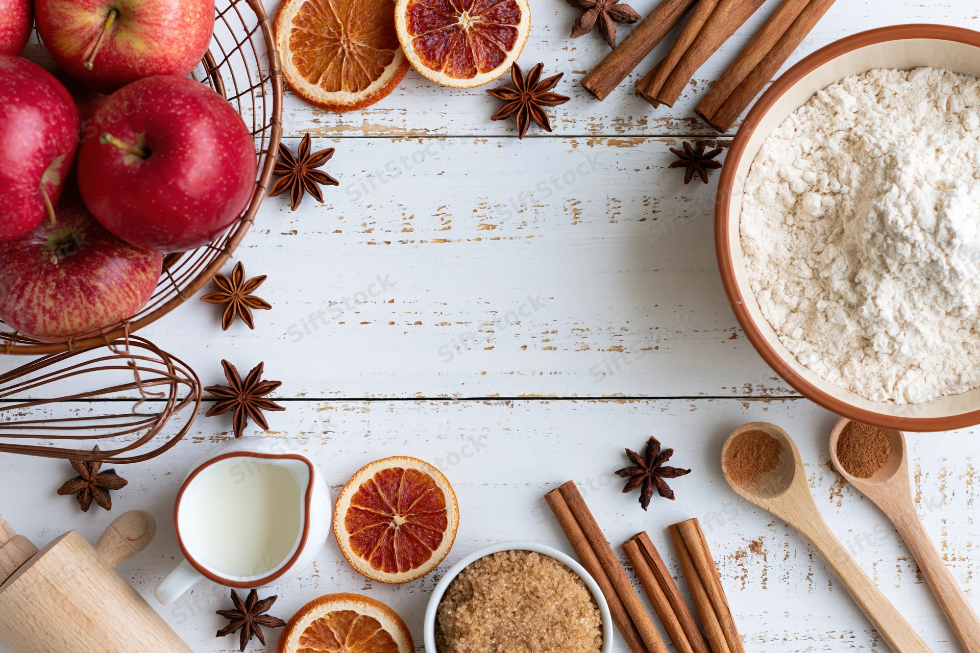 Baking ingredients arranged on a white wooden surface with copyspace in center