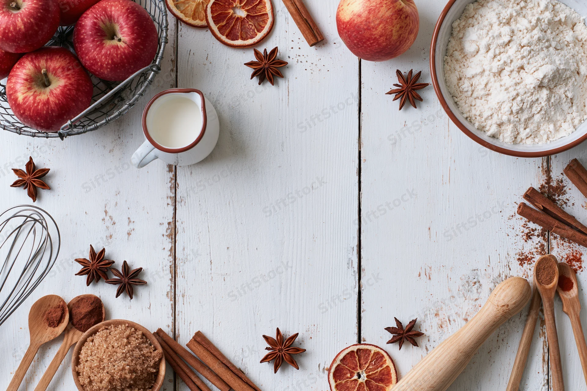 Baking ingredients arranged on white wooden table with copyspace in center