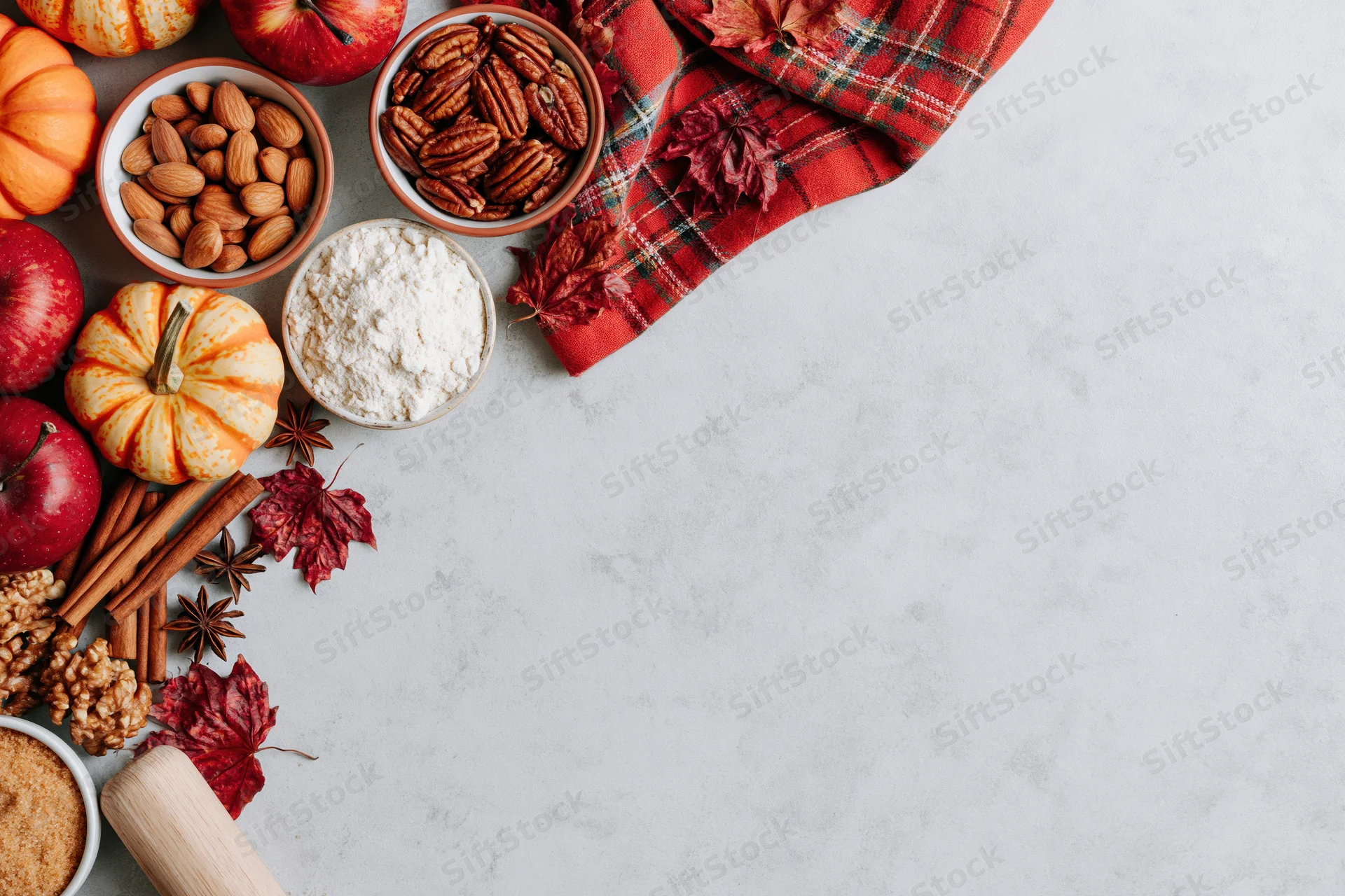 Autumn baking ingredients arranged on a marble countertop with plaid scarf and fall leaves