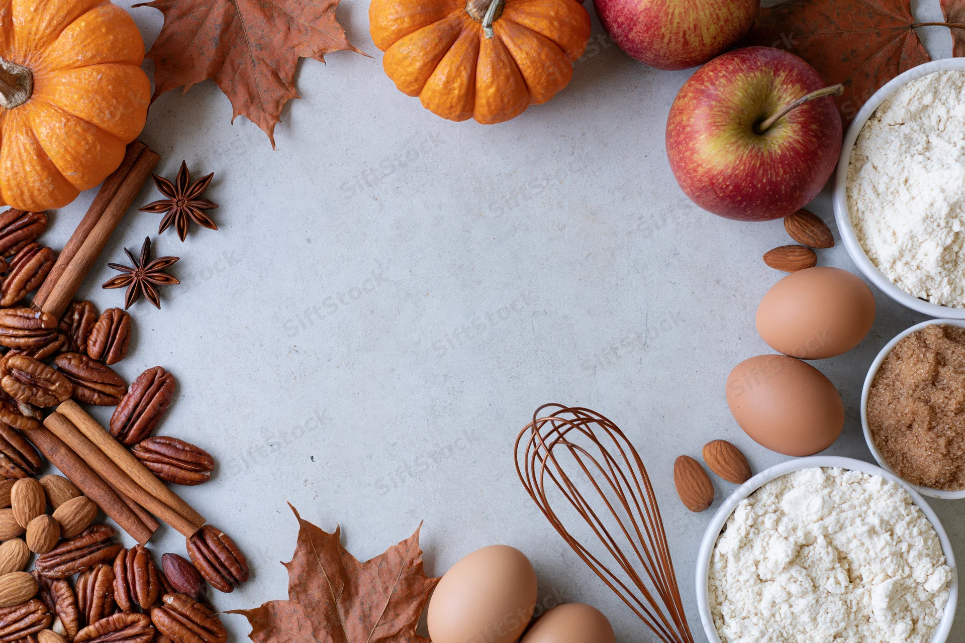 Autumn baking ingredients arranged around a central copyspace on a countertop