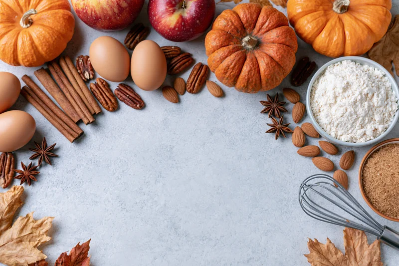 Autumn ingredients arranged around a gray countertop with copyspace for baking recipes