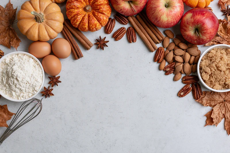 Autumn baking ingredients arranged on white surface with copyspace