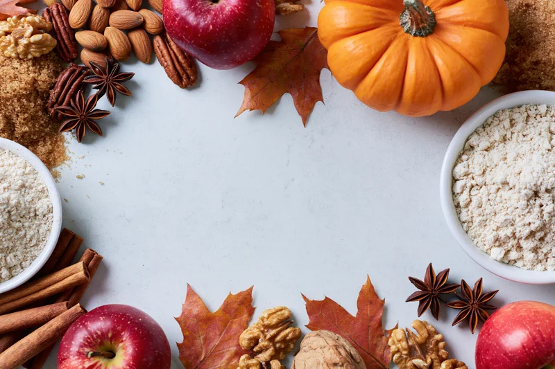 Autumn ingredients arranged in a border around a white surface with copyspace