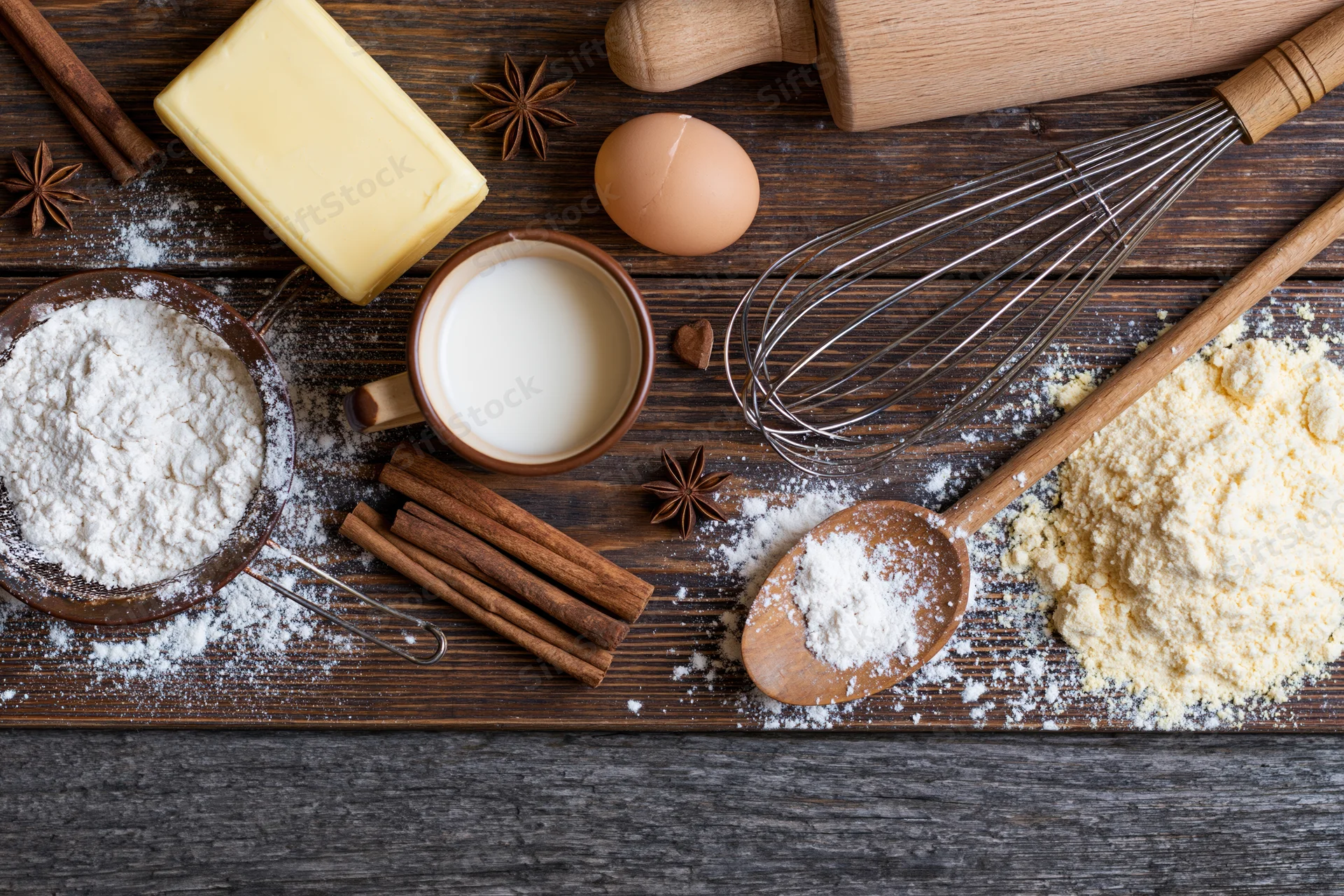 Baking ingredients arranged on a wooden countertop with copyspace at bottom