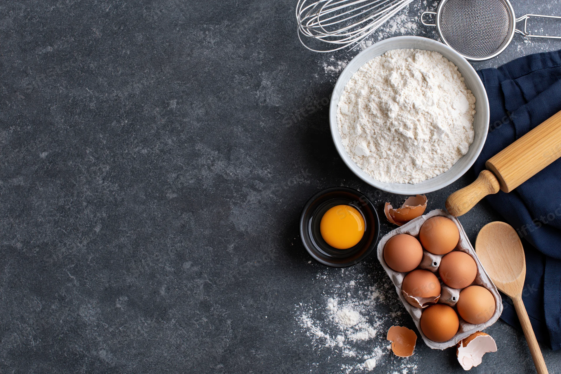 Baking ingredients arranged on dark textured countertop with copyspace