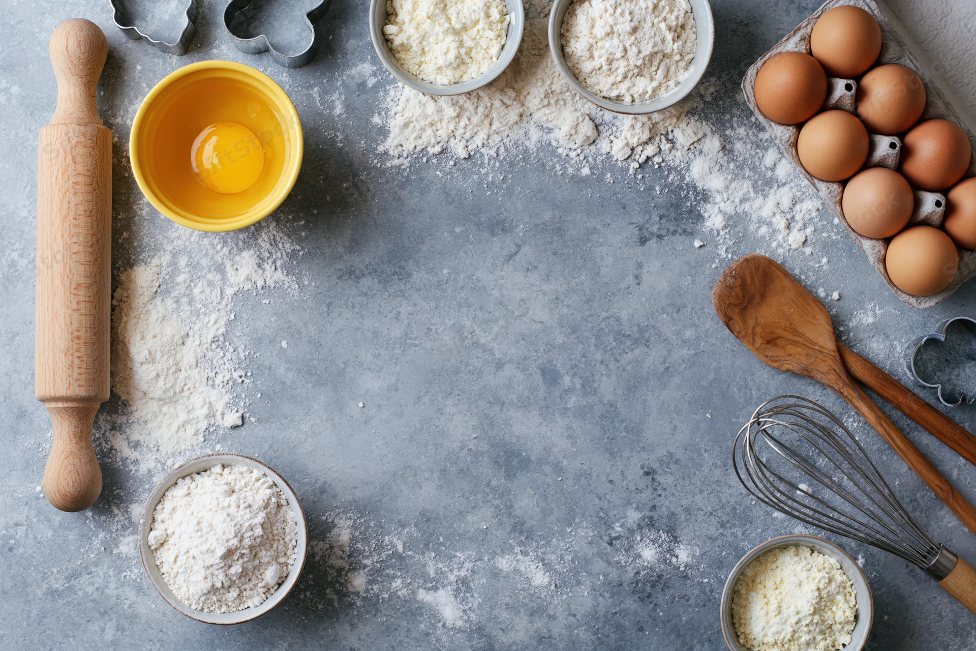 Baking ingredients arranged on a gray countertop with copyspace in center