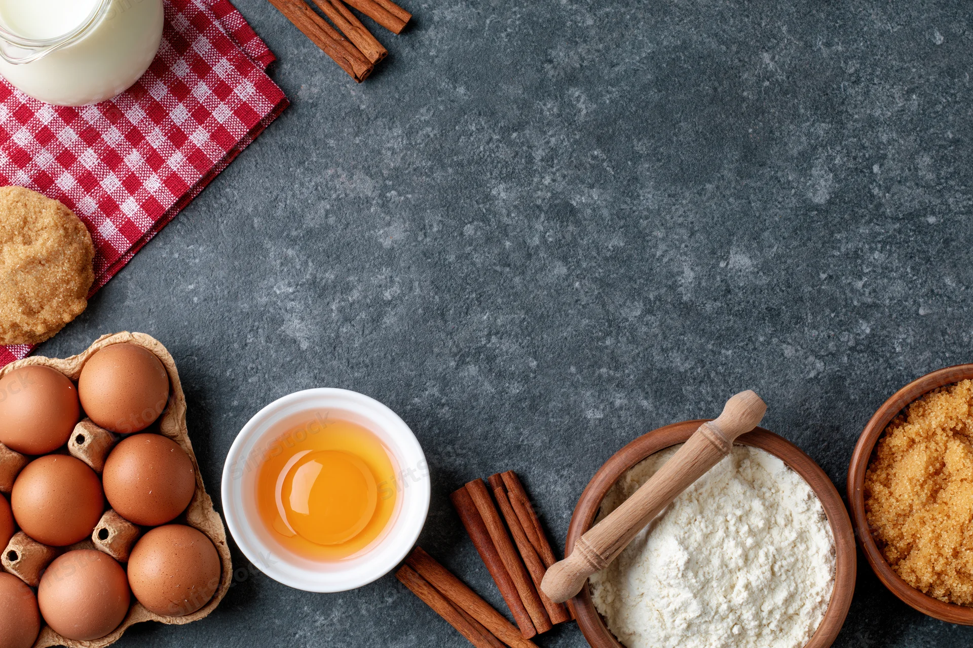 Baking ingredients arranged on dark countertop with copyspace
