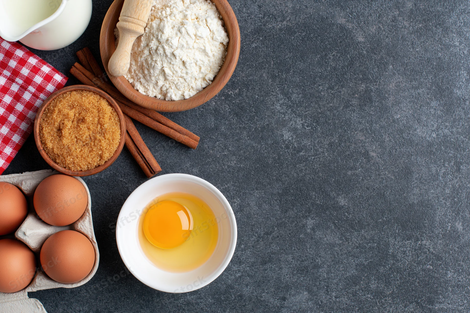 Baking ingredients arranged on dark countertop with copyspace