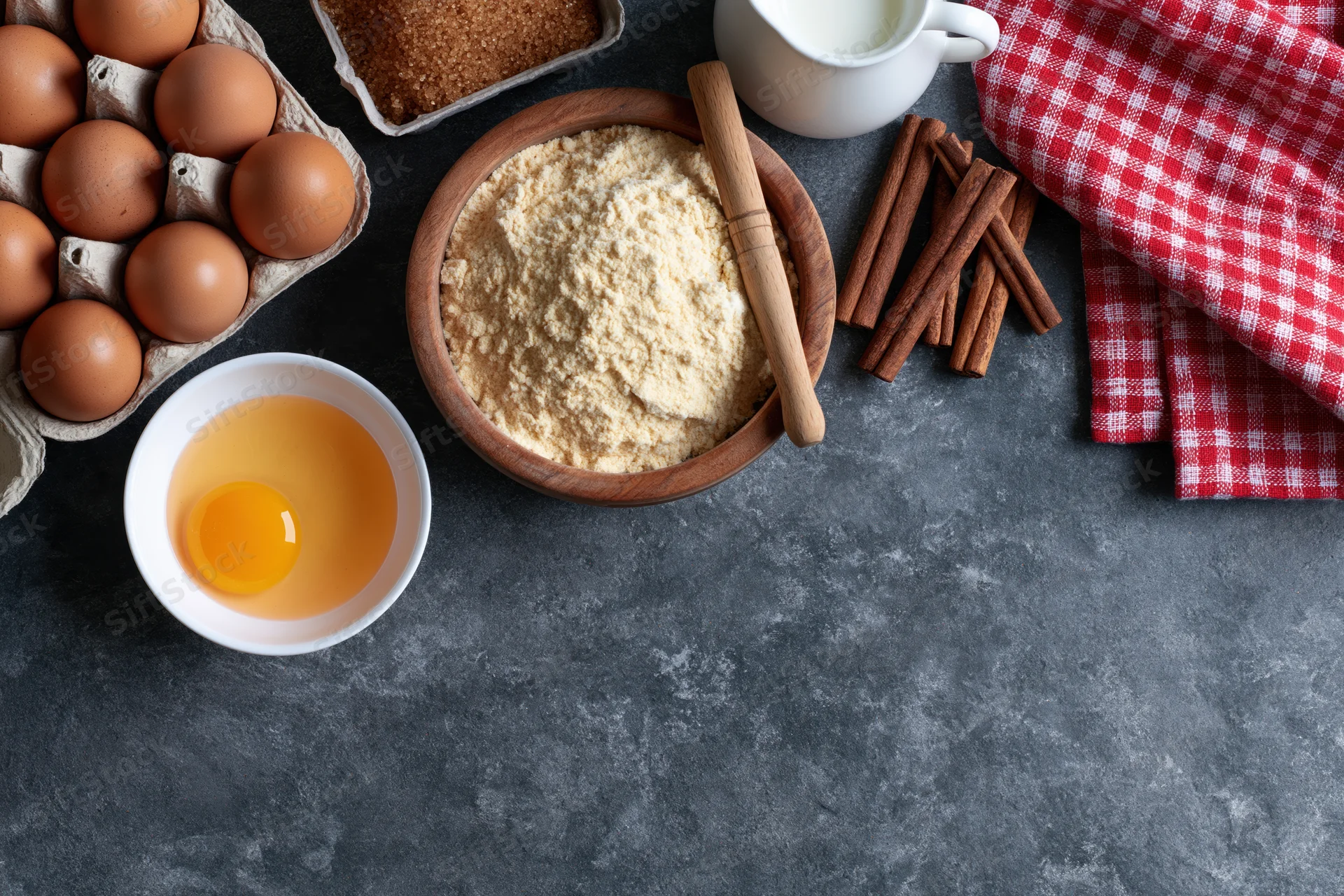 Baking ingredients arranged on dark countertop with copyspace