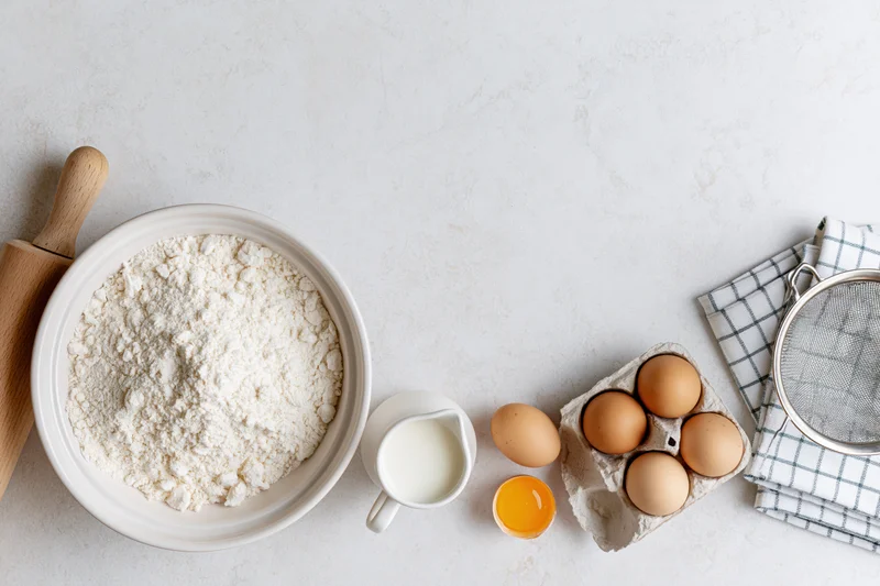 Baking ingredients arranged on a white countertop with copyspace