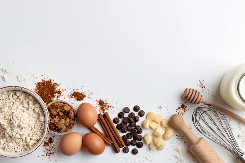 Baking ingredients arranged on white surface with copyspace