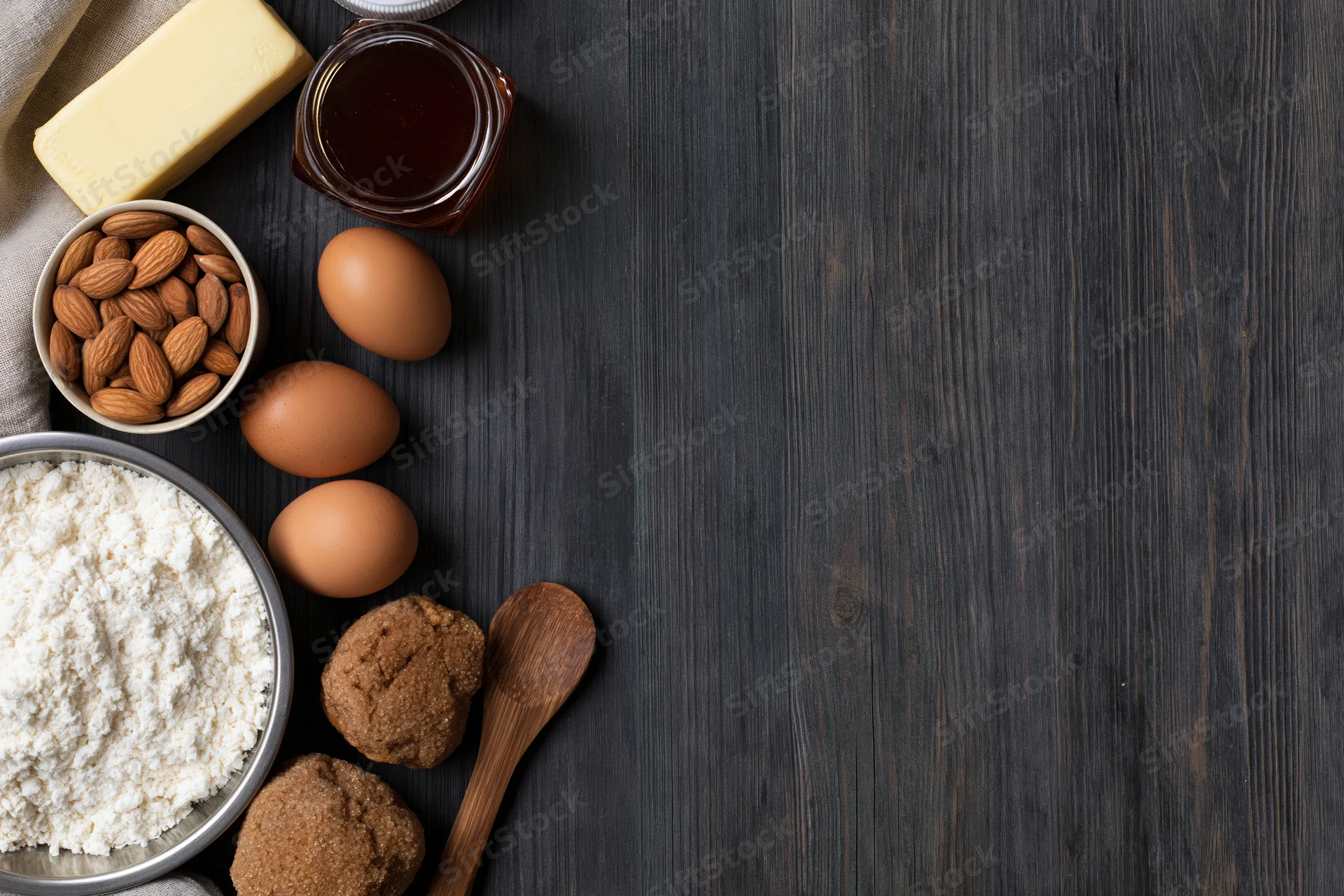 Baking ingredients arranged on dark wooden table with copyspace