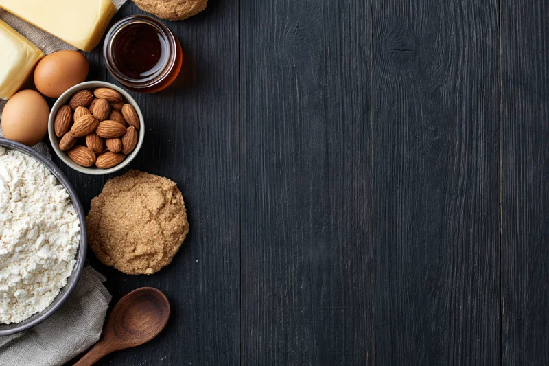 Baking ingredients arranged on dark wooden table with copyspace