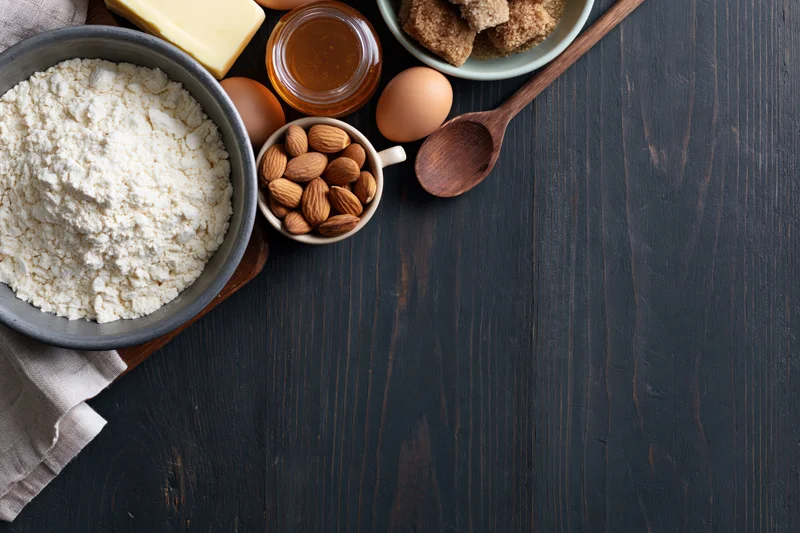 Baking ingredients arranged on dark wooden table with copyspace