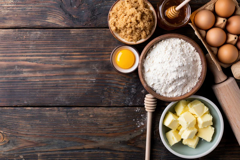 Baking ingredients arranged on a dark wooden table with copyspace on the left