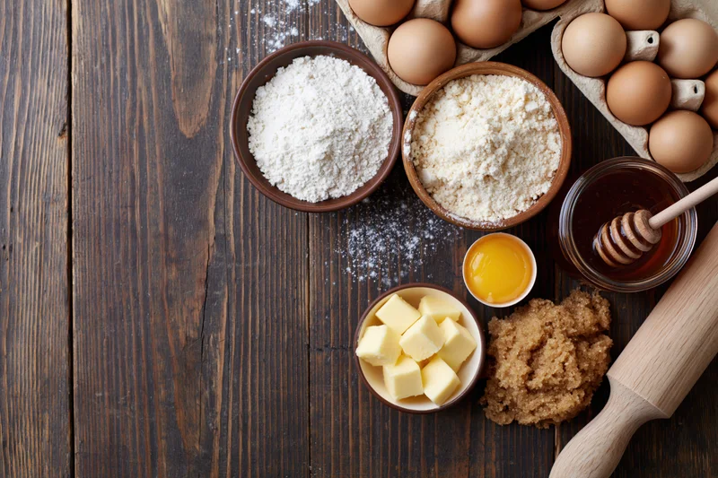 Baking ingredients arranged on a dark wooden table with copyspace on the left