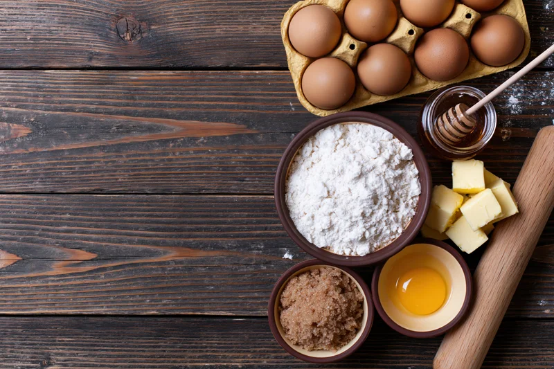 Baking ingredients arranged on a dark wooden table with copyspace on the left