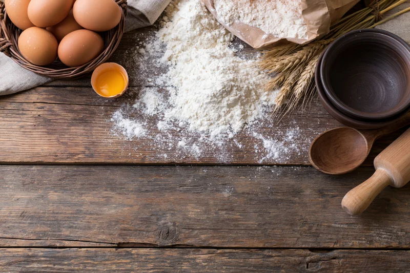 Baking ingredients arranged on a rustic wooden table with copyspace below
