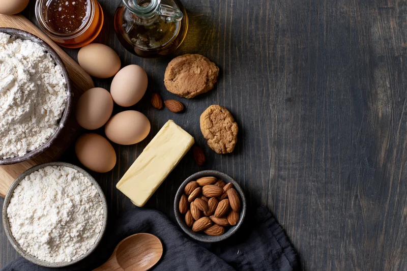 Baking ingredients arranged on dark wooden countertop with copyspace
