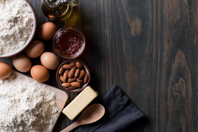 Baking ingredients arranged on dark wooden table with copyspace