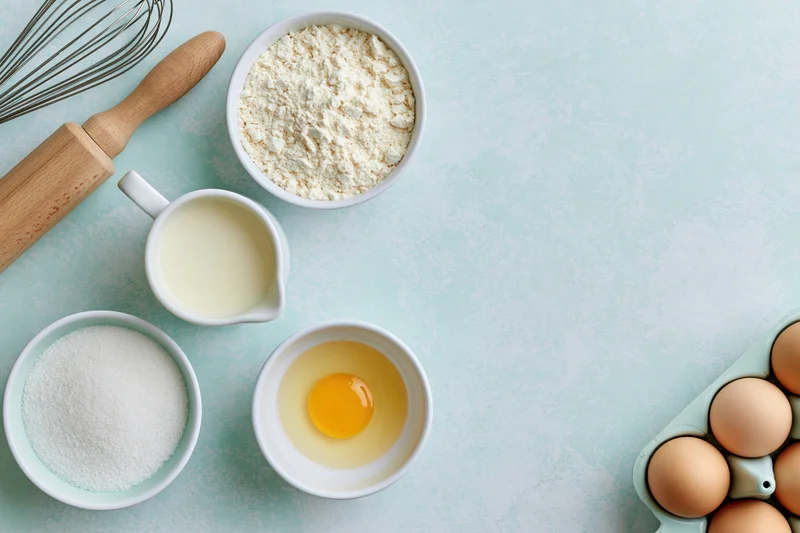 Baking ingredients arranged on a light blue countertop with copyspace