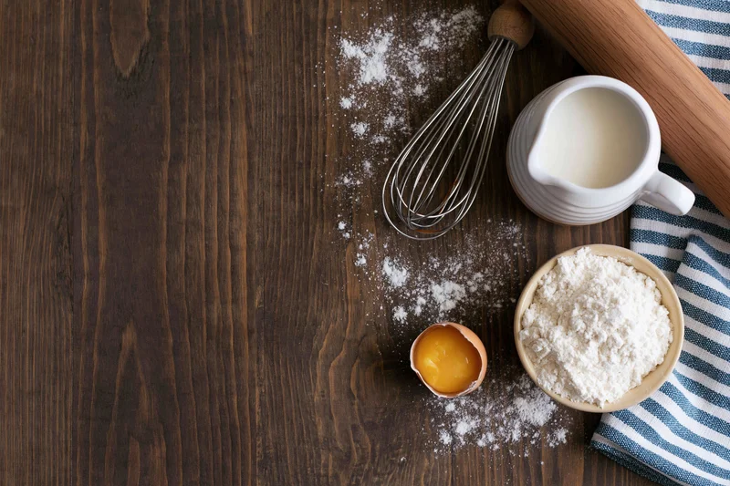 Baking ingredients arranged on a wooden countertop with copyspace