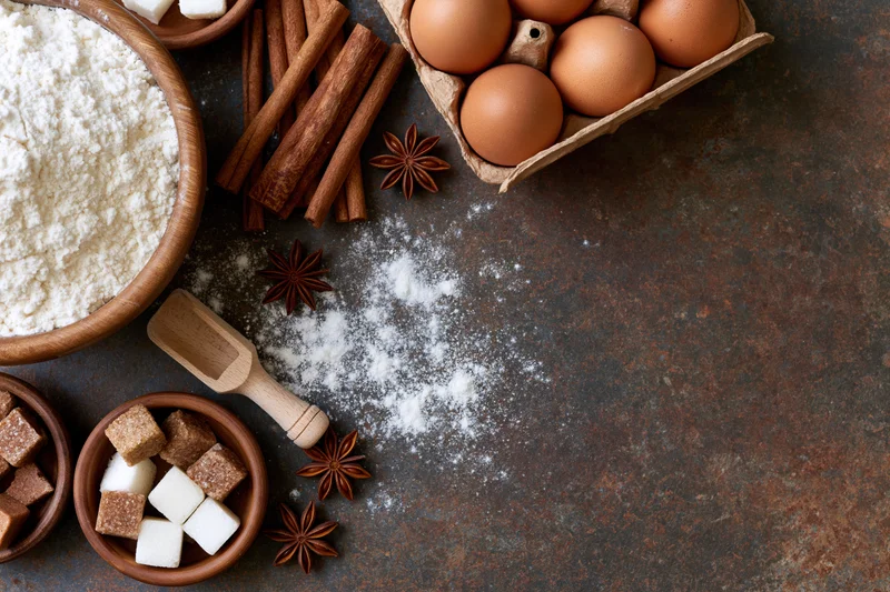 Baking ingredients arranged on a dark rustic surface with copyspace
