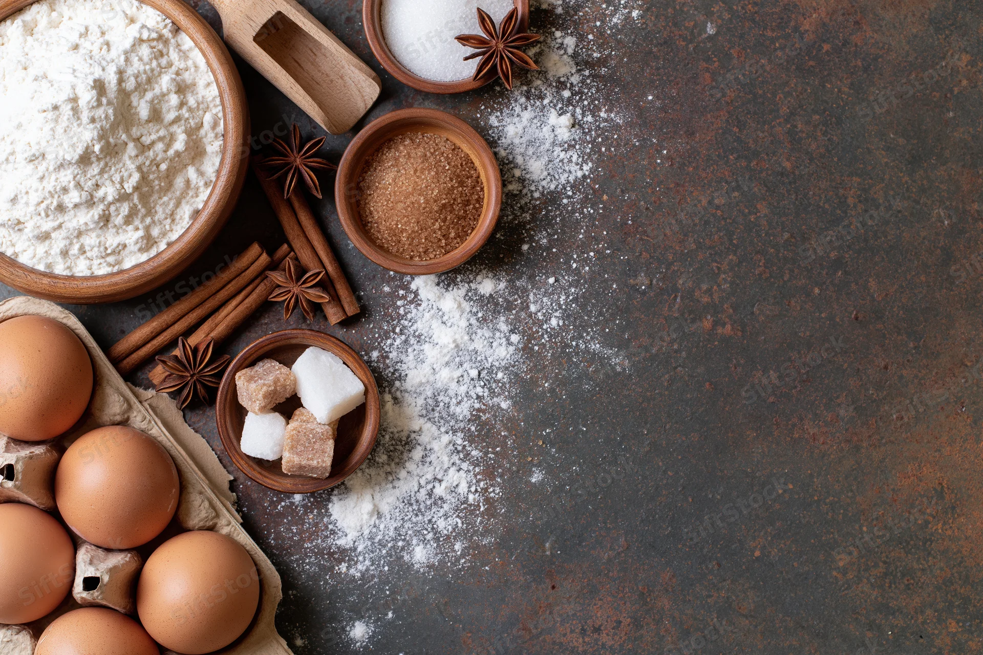 Baking ingredients arranged on a dark rustic surface with copyspace