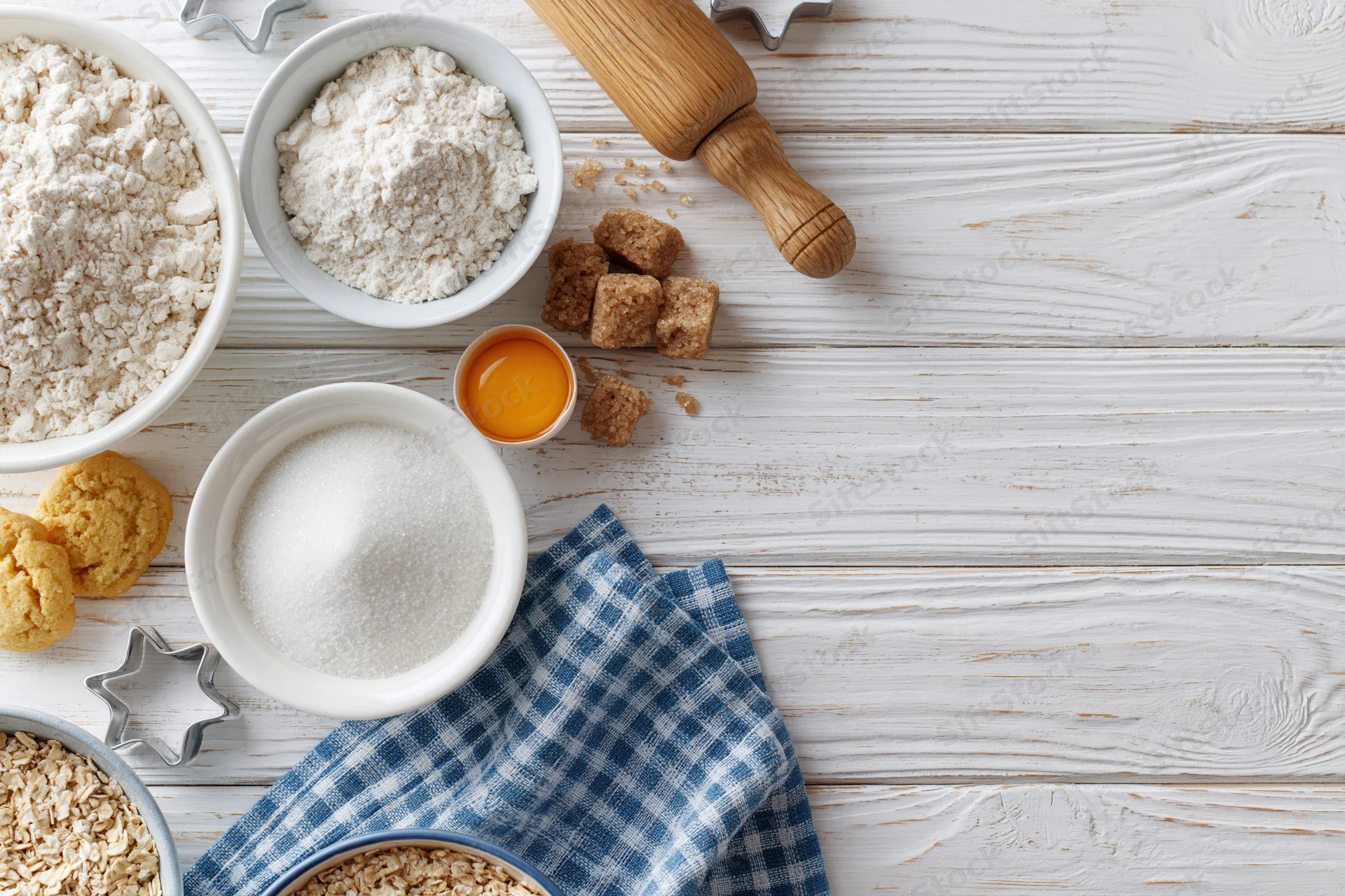 Baking ingredients arranged on a white wooden surface with copyspace